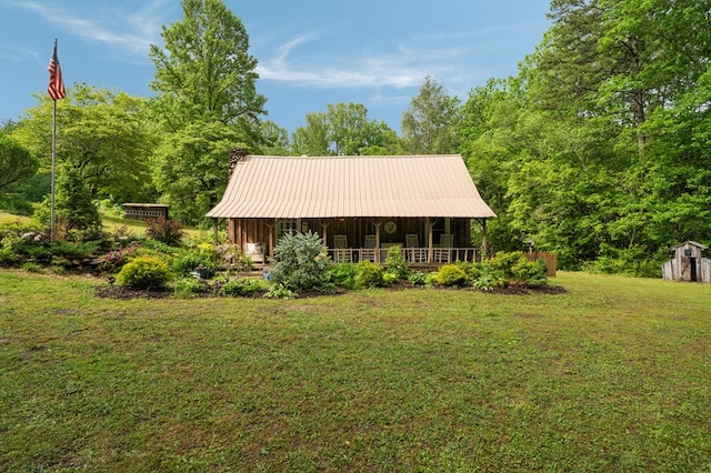 view of front of property with a front yard, a storage unit, an outdoor structure, metal roof, and covered porch