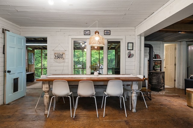 dining room with dark wood-style floors, wood walls, and a wood stove