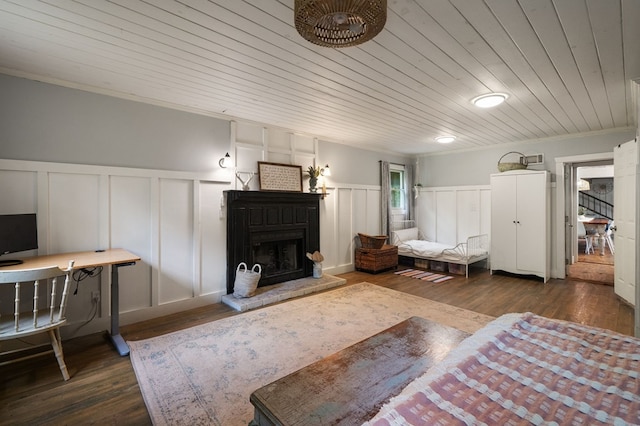 bedroom with a decorative wall, wainscoting, wood finished floors, wood ceiling, and a fireplace