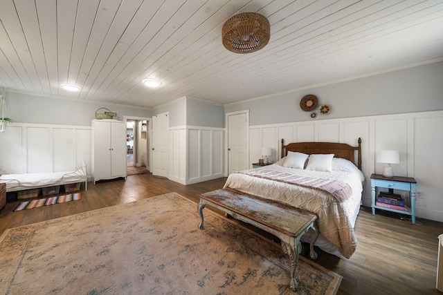 bedroom featuring a decorative wall, wood finished floors, wainscoting, wooden ceiling, and ornamental molding