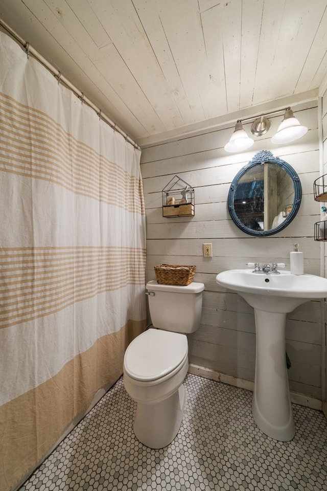 bathroom with wood ceiling, toilet, a sink, wooden walls, and a shower with shower curtain