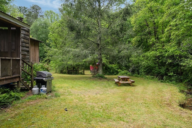 view of green lawn with a forest view