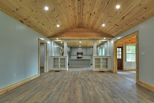 unfurnished living room featuring vaulted ceiling, baseboards, recessed lighting, decorative columns, and wood finished floors
