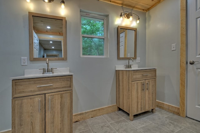 bathroom with two vanities, tile patterned flooring, a sink, and baseboards