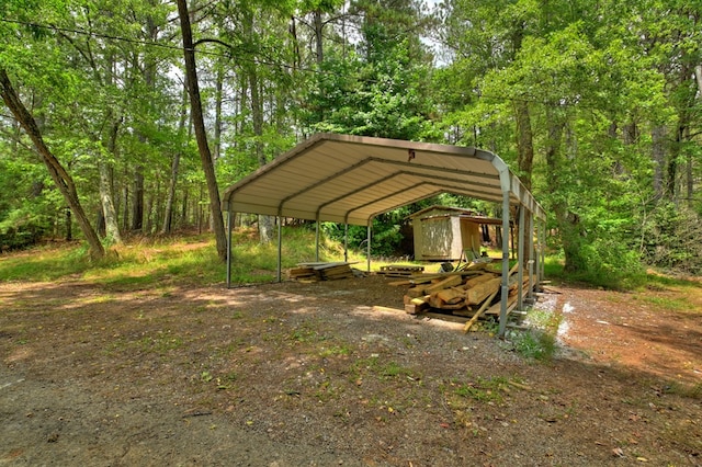 view of yard featuring a view of trees, an outbuilding, a carport, and a storage shed
