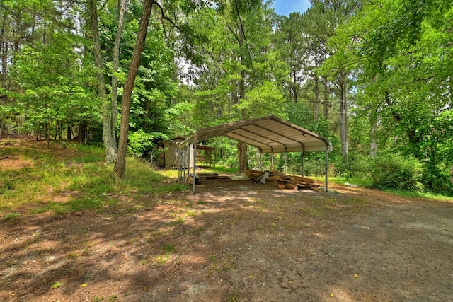view of yard featuring a carport and dirt driveway