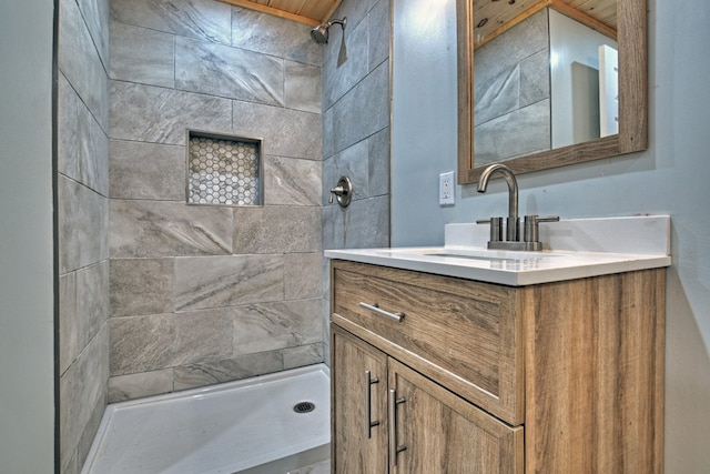 full bathroom featuring a tile shower and vanity