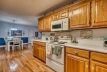 kitchen with light wood-type flooring, stainless steel range with electric cooktop, hanging light fixtures, and an inviting chandelier