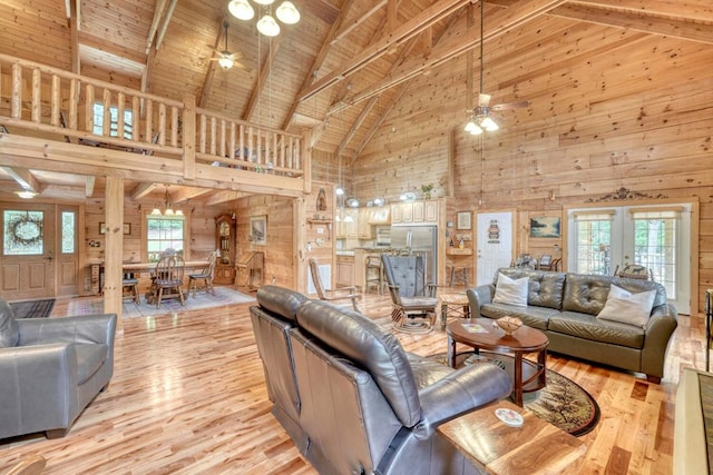 living room with light hardwood / wood-style flooring, ceiling fan, wooden walls, a wealth of natural light, and wooden ceiling