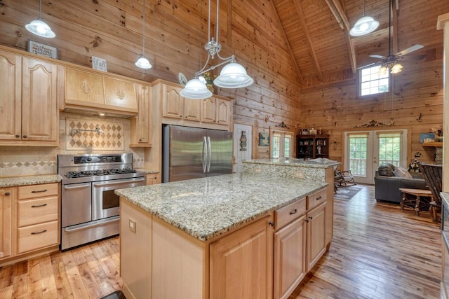 kitchen with appliances with stainless steel finishes, light brown cabinetry, and hanging light fixtures