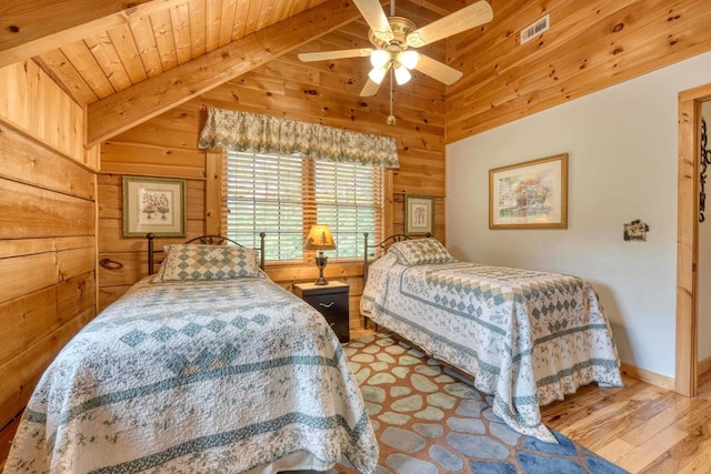 bedroom with wood walls, vaulted ceiling with beams, ceiling fan, light hardwood / wood-style floors, and wooden ceiling