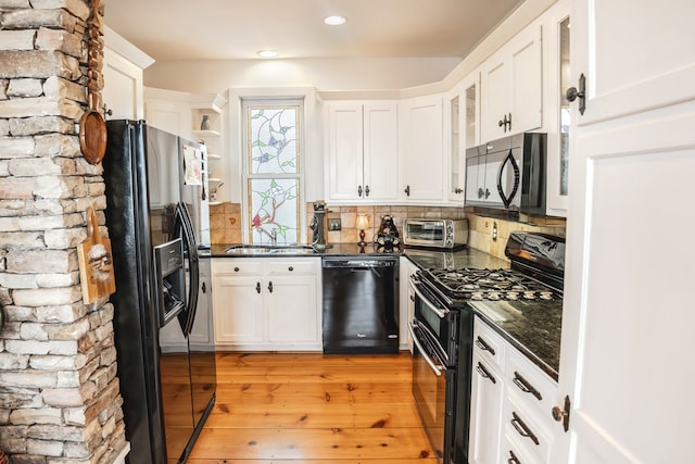 kitchen with tasteful backsplash, sink, white cabinets, light hardwood / wood-style floors, and black appliances