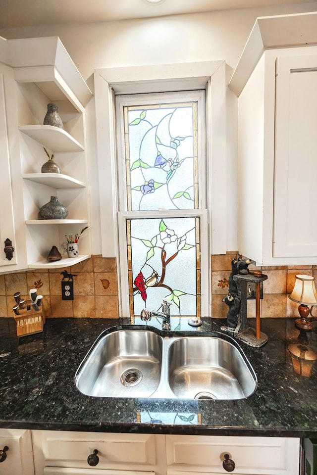 kitchen featuring sink, backsplash, dark stone counters, and white cabinets