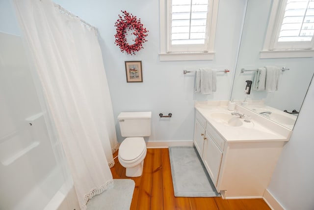 full bathroom featuring wood-type flooring, a healthy amount of sunlight, vanity, and toilet