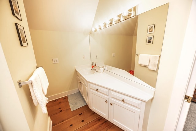 bathroom with lofted ceiling, hardwood / wood-style floors, and vanity