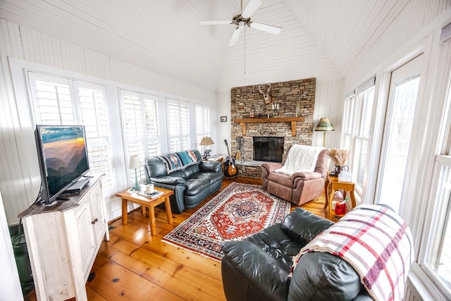 living room featuring lofted ceiling, a stone fireplace, wood-type flooring, and plenty of natural light