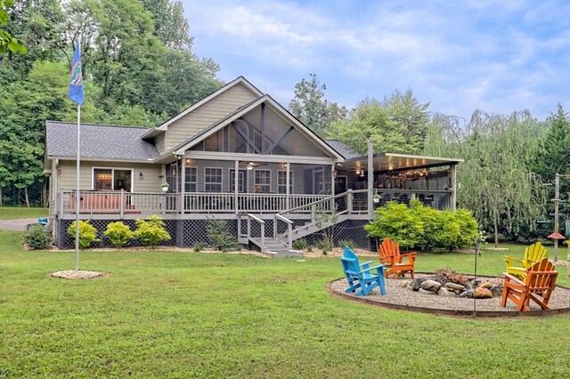 back of property with an outdoor fire pit, a yard, a sunroom, and a deck