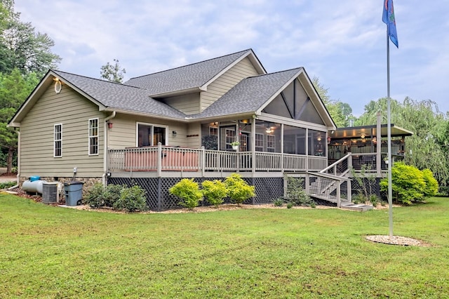 rear view of house with a deck, cooling unit, a sunroom, and a yard