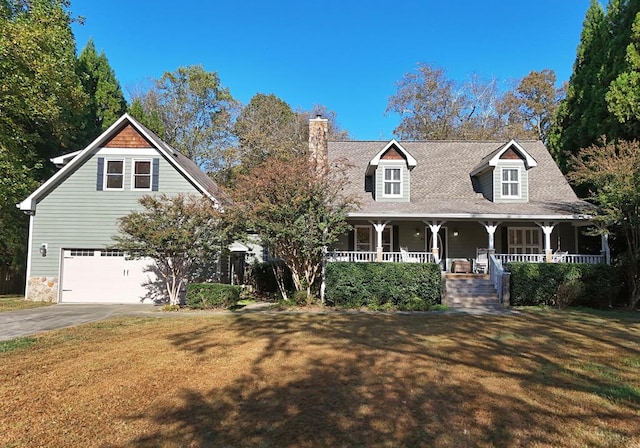 view of front of property featuring covered porch, a garage, and a front yard