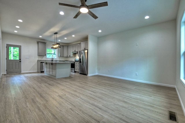 kitchen featuring appliances with stainless steel finishes, gray cabinets, baseboards, open floor plan, and visible vents