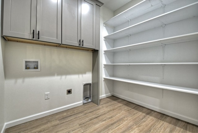 washroom with washer hookup, hookup for an electric dryer, light wood-type flooring, cabinet space, and baseboards
