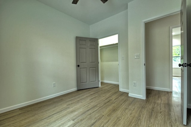 unfurnished bedroom featuring baseboards, a ceiling fan, wood finished floors, and vaulted ceiling