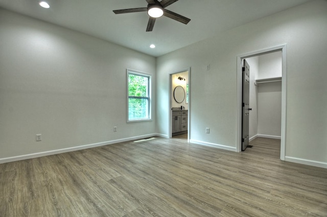 unfurnished bedroom with baseboards, recessed lighting, light wood-style flooring, and a spacious closet
