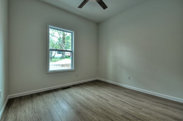 empty room with ceiling fan, dark wood finished floors, baseboards, and visible vents