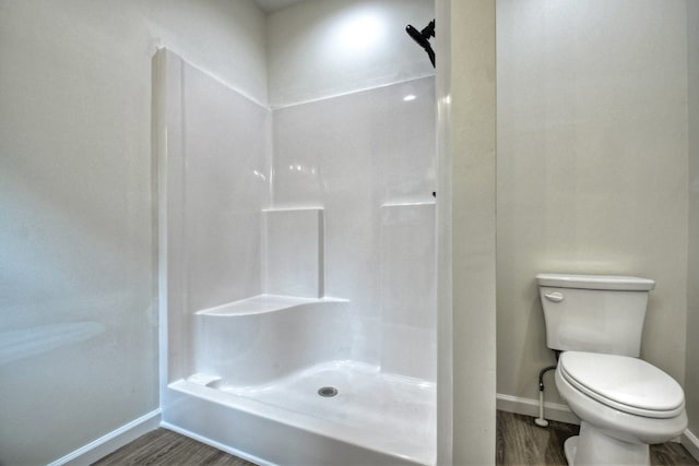 bathroom featuring a shower, baseboards, toilet, and wood finished floors