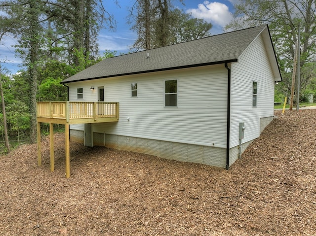 rear view of property featuring roof with shingles and a deck