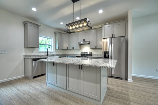 kitchen featuring a center island, stainless steel appliances, baseboards, under cabinet range hood, and gray cabinetry