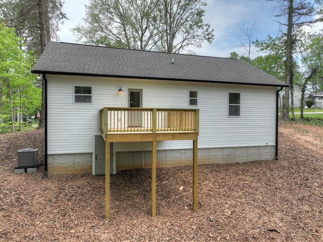 rear view of property with roof with shingles, a wooden deck, and cooling unit