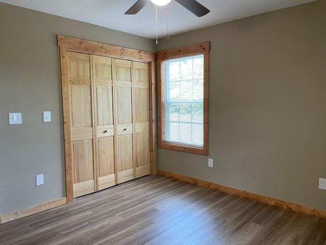 unfurnished bedroom featuring hardwood / wood-style floors, ceiling fan, and a closet