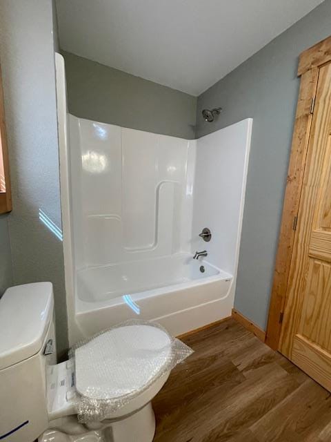 bathroom with toilet, hardwood / wood-style flooring, and shower / washtub combination