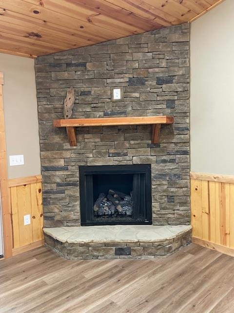 interior details with wood walls, hardwood / wood-style flooring, wooden ceiling, and a stone fireplace