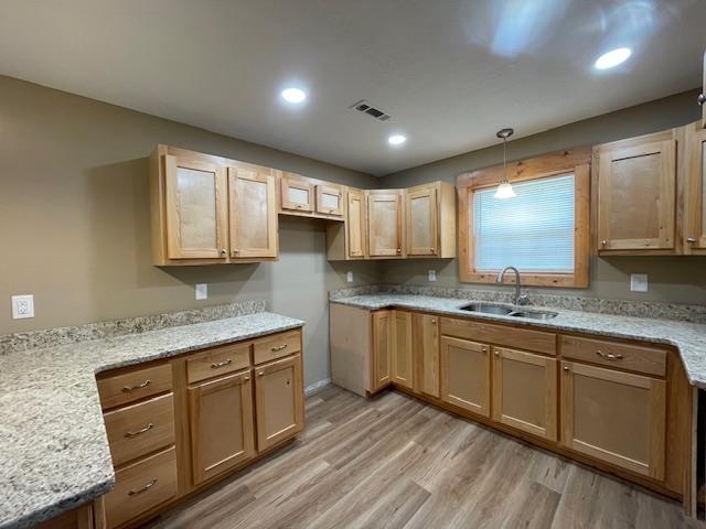 kitchen featuring light wood-type flooring, pendant lighting, and sink