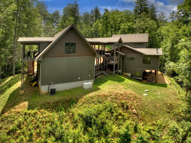 rear view of property with a yard and central air condition unit