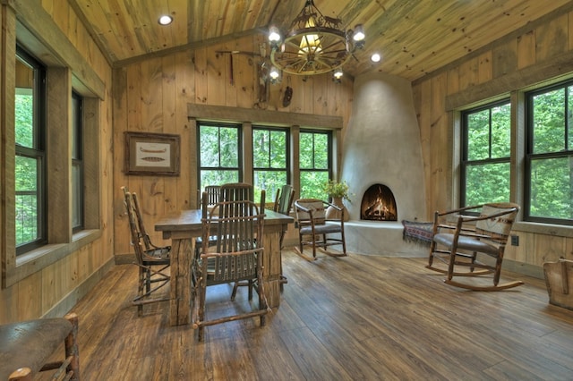 dining area featuring a large fireplace, wooden ceiling, dark hardwood / wood-style flooring, and wood walls