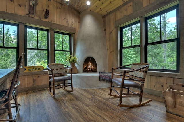 living area featuring vaulted ceiling, wooden walls, a fireplace, hardwood / wood-style flooring, and wood ceiling