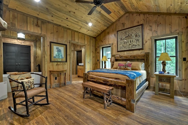 bedroom featuring wood ceiling, hardwood / wood-style flooring, high vaulted ceiling, connected bathroom, and wood walls