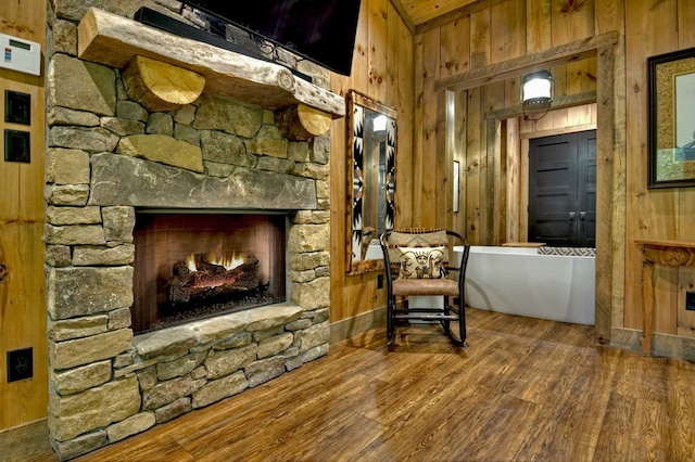 sitting room with wood-type flooring, a fireplace, and wood walls