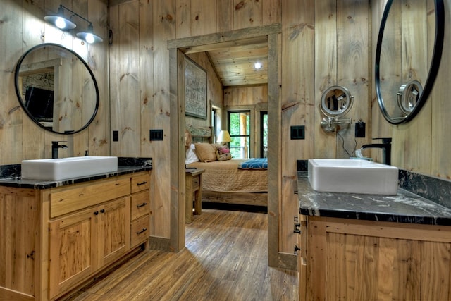 bathroom with wooden ceiling, hardwood / wood-style floors, vanity, and wood walls