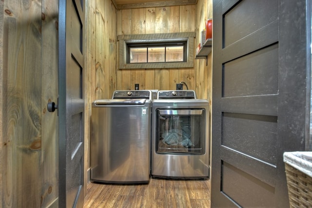 clothes washing area with hardwood / wood-style flooring, wooden walls, and washer and clothes dryer