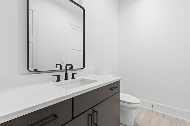 bathroom with hardwood / wood-style flooring, vanity, and toilet