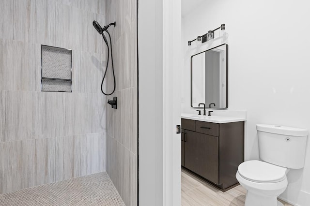 bathroom with a tile shower, tile patterned flooring, vanity, and toilet