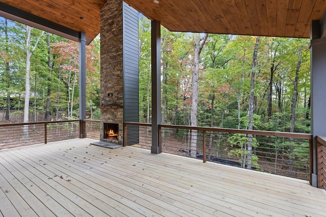 wooden terrace with an outdoor stone fireplace