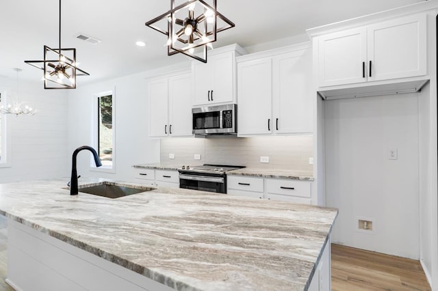 kitchen with white cabinetry, sink, stainless steel appliances, and decorative light fixtures