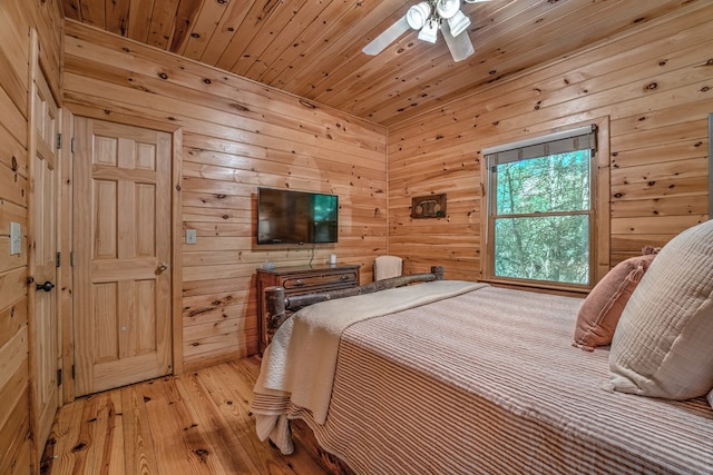 bedroom featuring wooden walls, wooden ceiling, a ceiling fan, and light wood-style floors