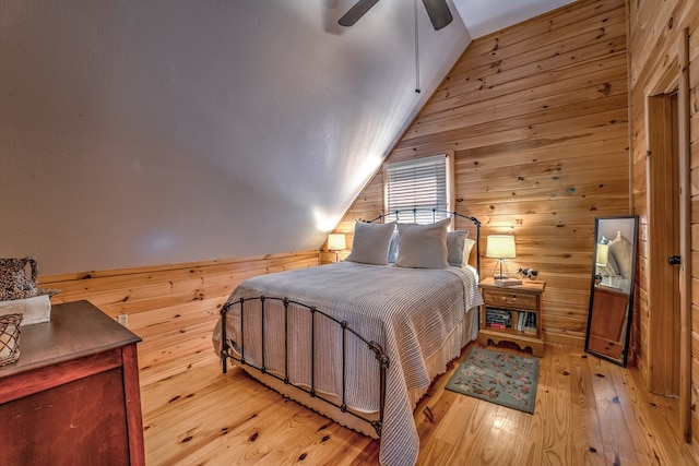 bedroom with lofted ceiling, light wood-style floors, wooden walls, and a ceiling fan