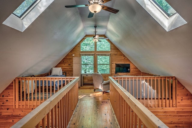 bonus room featuring lofted ceiling with skylight, wood walls, and wood finished floors